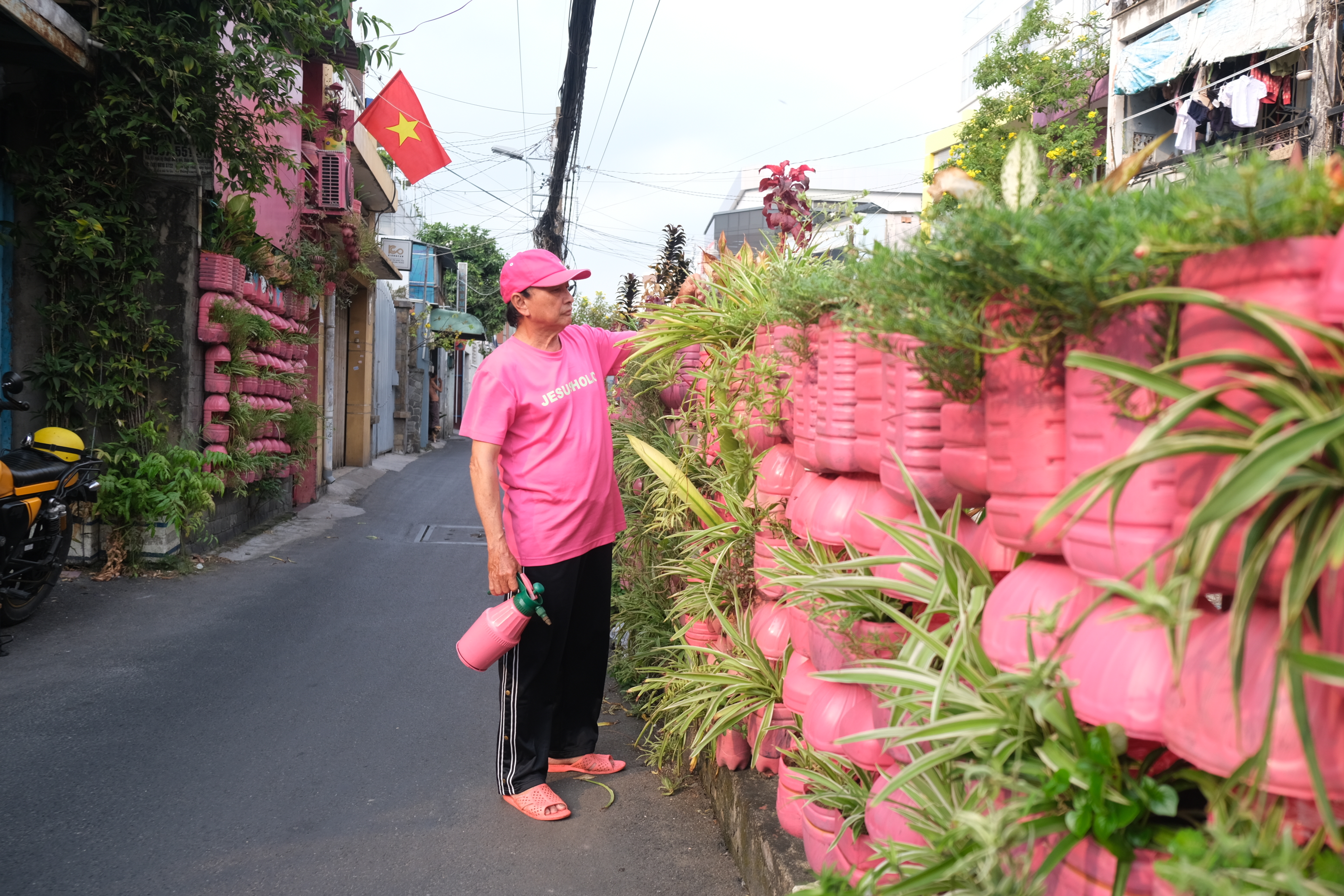 Chanh takes care of flower pots hung on the rail protection fence in front of his house  in Phu Nhuan District, Ho Chi Minh City. Photo: Ngoc Phuong / Tuoi Tre News