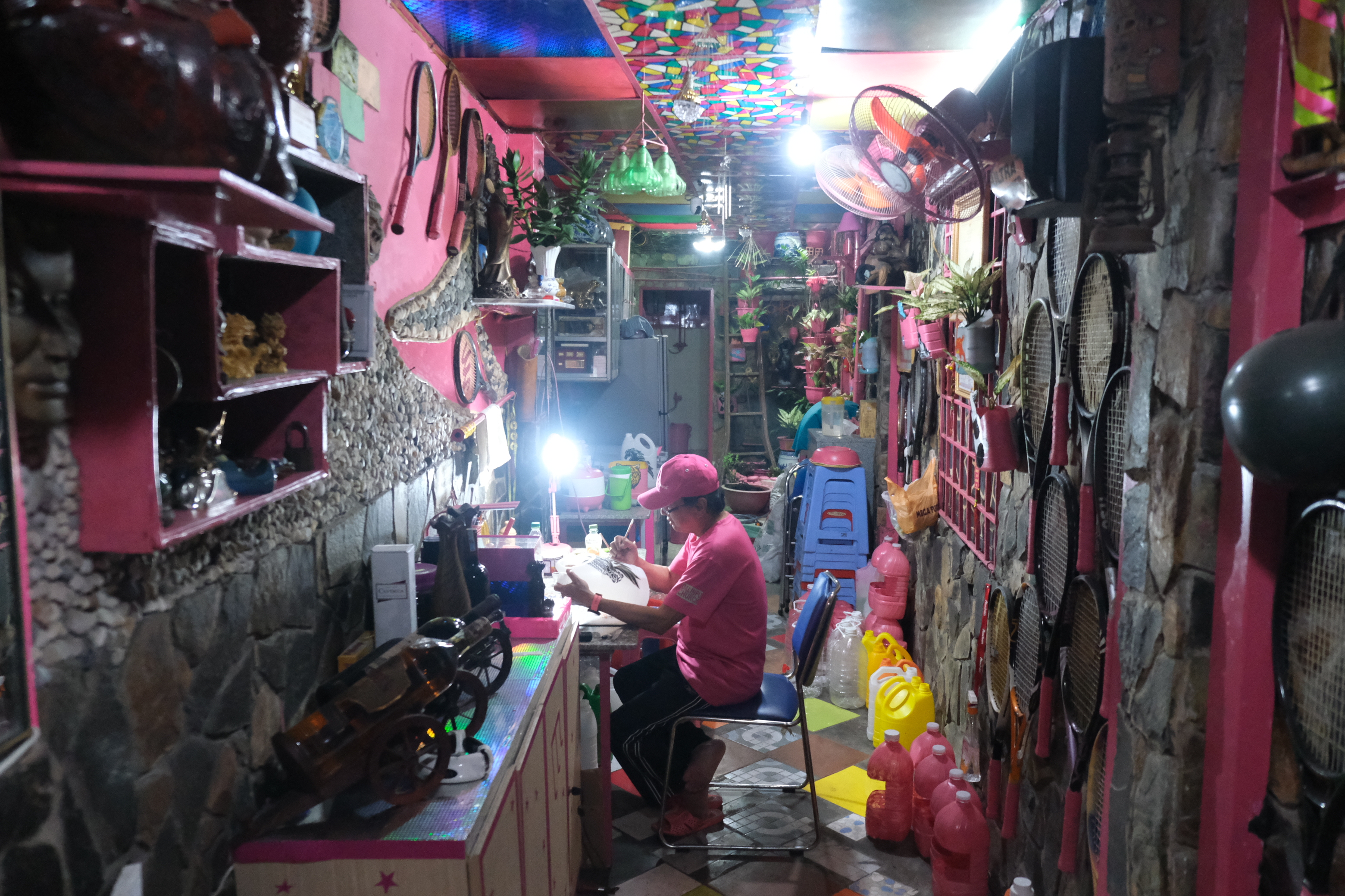 Chanh works on a discarded plastic bottle in his house which is home to many pink items. Photo: Ngoc Phuong / Tuoi Tre News