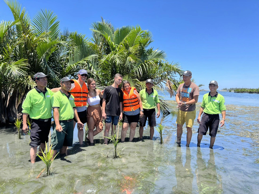 Foreign tourists and Jack Tran Tours’ employees take a picture after planting nipa palm saplings into Cam Thanh nipa palm forest, in Cam Thanh Commune, Hoi An City, Quang Nam Province, central Vietnam. Photo: K.T. / Tuoi Tre