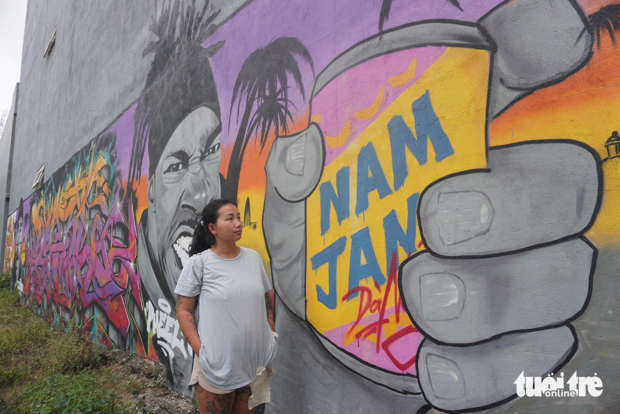 N.T.H. stands next to a graffiti painting on the wall of a house in Hoa Hai Ward, Ngu Hanh Son District, Da Nang City, central Vietnam. Photo: Doan Nhan / Tuoi Tre