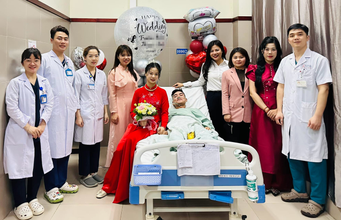 N.A. (wearing a red 'ao dai'), her husband T.H., and their loved ones and medical team pose for a photo during their hospital bedside wedding at Lang Son General Hospital in Lang Son Province, northern Vietnam, March 22, 2024. Photo: Supplied