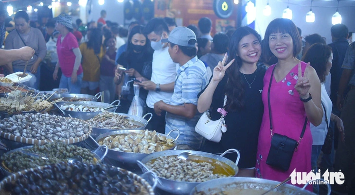 Two visitors pose for a photo at the booth of shellfish dishes at the culinary culture fest in Binh Dinh Province’s Quy Nhon City, south-central Vietnam, March 22, 2024. Photo: Lam Thien / Tuoi Tre