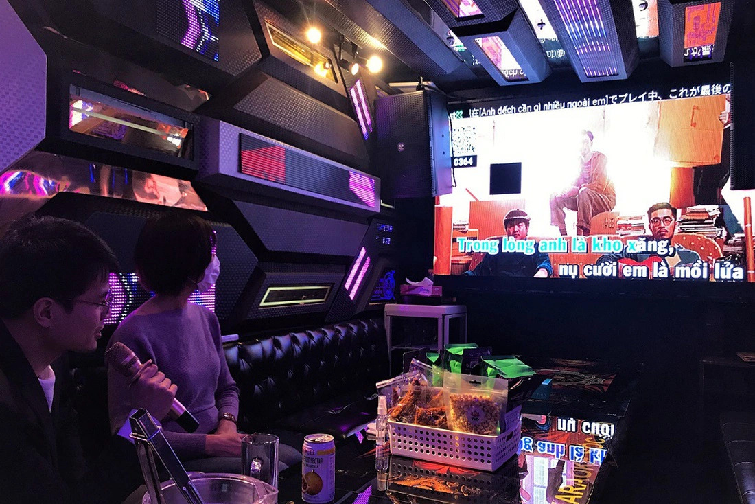 Two people enjoy a full-packaged modern karaoke service, usually including a karaoke machine, a sound-proof room, and an assortment of food and drinks. Photo: KokoroVJ