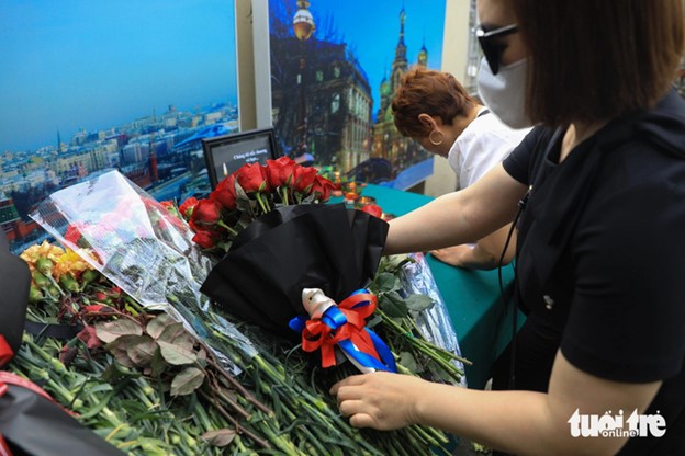 A Hanoi woman lays a bouquet of flowers with a ribbon having colors of the Russian flag in front of the Russian Embassy in Hanoi. Photo: Danh Khang / Tuoi Tre