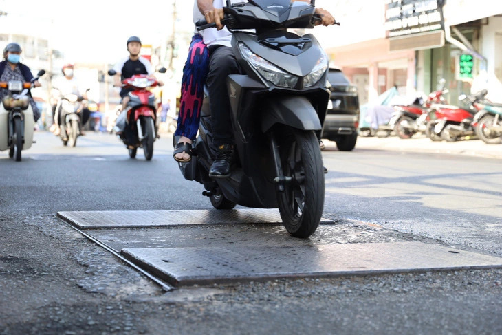 A motorcycle runs over two visibly protruding manhole covers on Kha Van Can Street, Thu Duc City under Ho Chi Minh City. Photo: Ngoc Nhi / Tuoi Tre