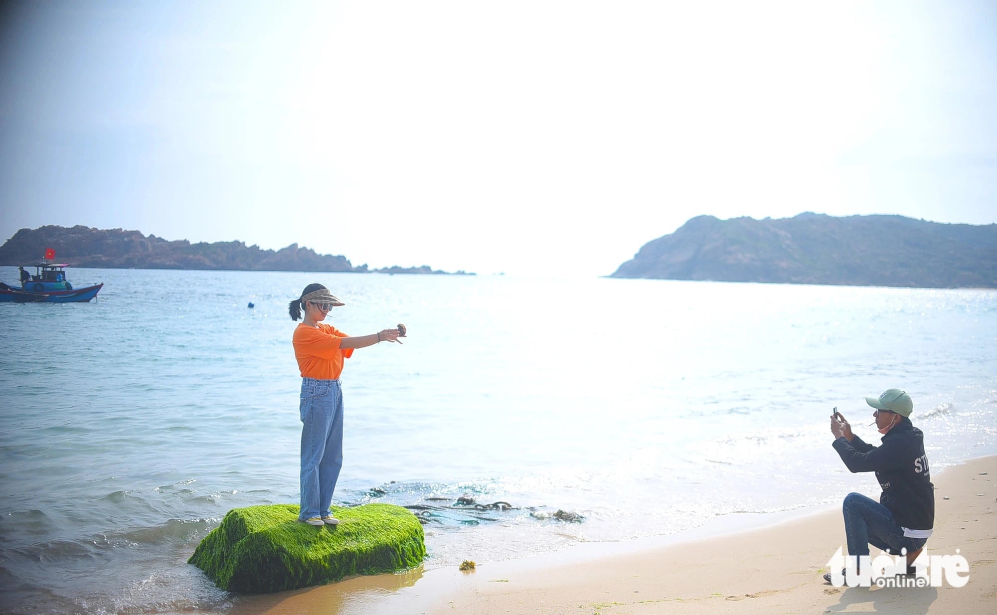 A man takes a photo of a woman while visiting a moss-covered reef at a beach in Nhon Hai Commune, Quy Nhon City, Binh Dinh Province, central Vietnam in this illustration photo. Photo: Lam Thien / Tuoi Tre