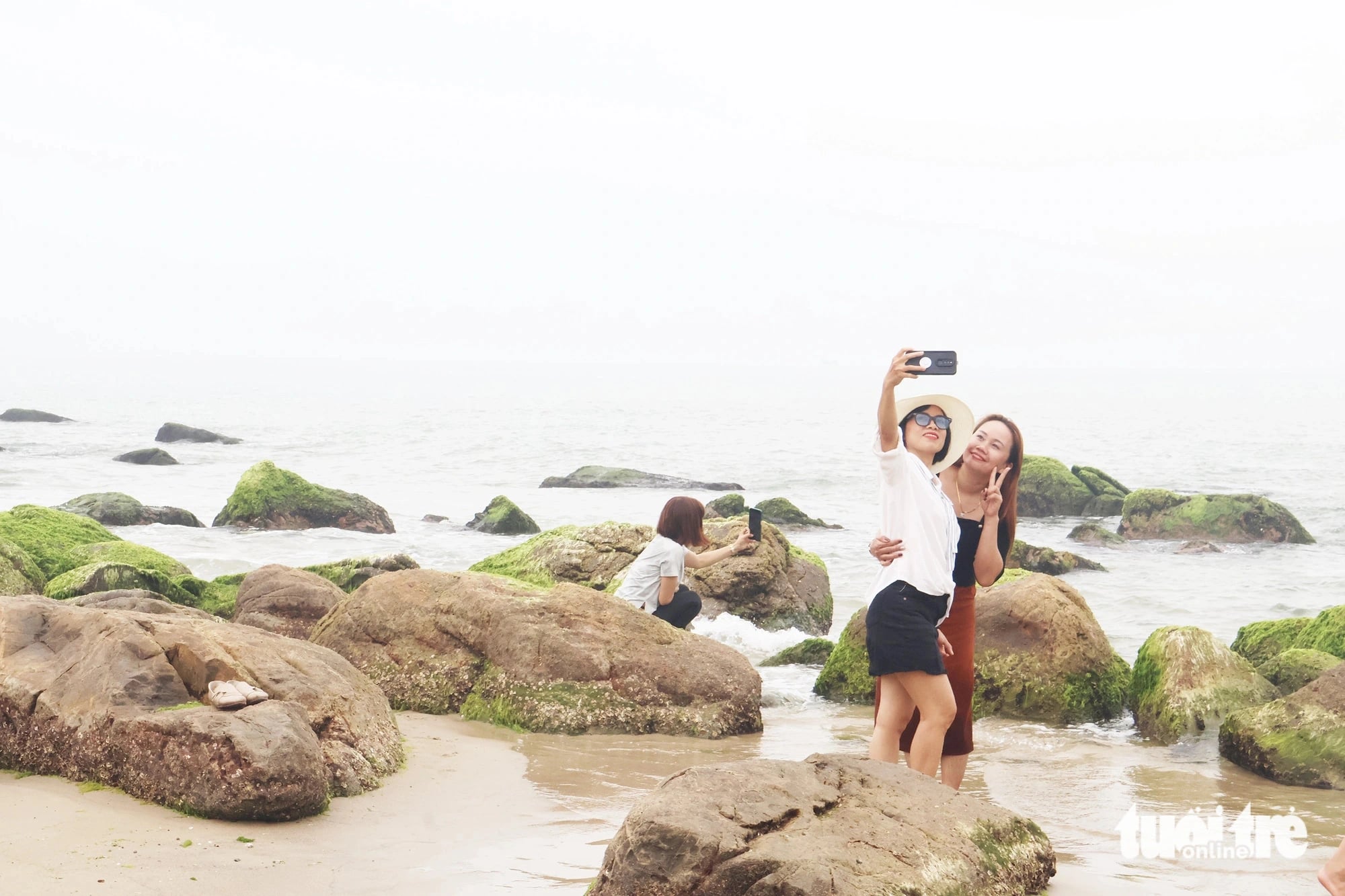 Tourists take photos while visiting a moss-covered reef at Nam O Beach, Lien Chieu District, Da Nang City, central Vietnam in this illustration photo. Photo: Le Trung / Tuoi Tre