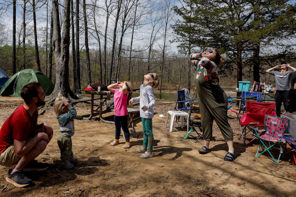 Members of the Debenham family and friends, who travelled from Utah, Las Vegas, and Illinois to experience the total solar eclipse together, try out their eclipse viewing glasses at their campsite a day ahead of the event at Camp Carew in Makanda, Illinois, U.S., April 7, 2024. Photo: Reuters