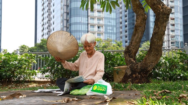 The 80-year-old Pham Thi Ngoc reads newspapers under a tree along the Nhieu Loc – Thi Nghe Canal in Binh Thanh District.