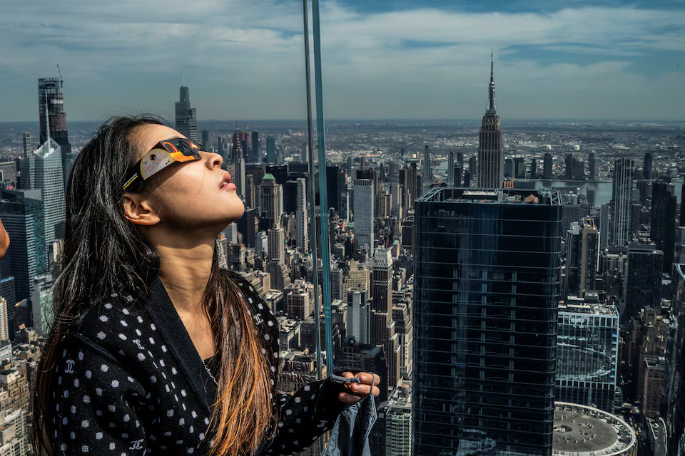 A woman looks at the start of the eclipse as people gather on the observation deck of Edge at Hudson Yards during a partial solar eclipse in New York City, New York, U.S., April 8, 2024. Photo: Reuters