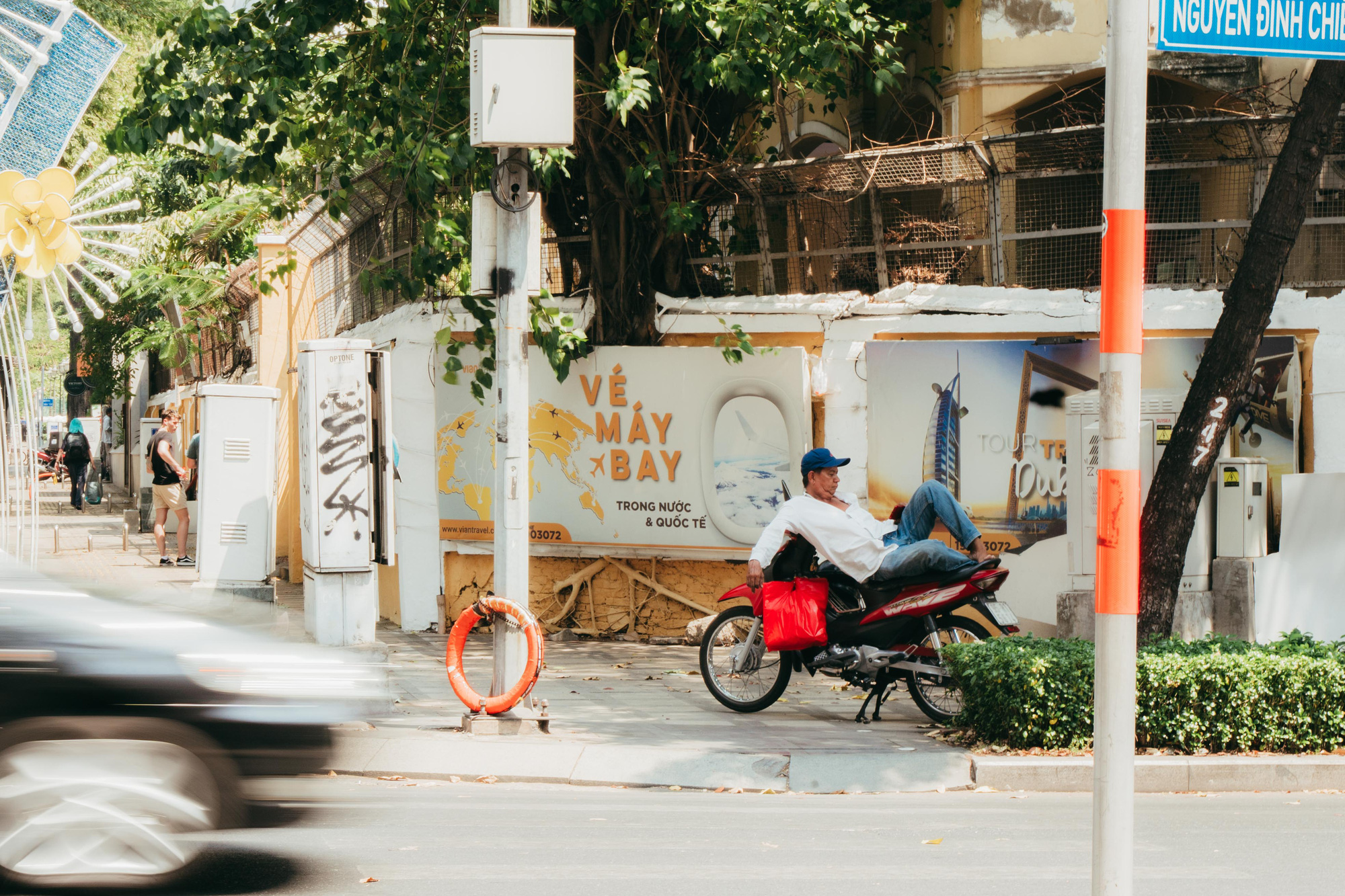 A ride-hailing driver takes a respite under a tree shade in Ho Chi Minh City. Photo: Thanh Hiep / Tuoi Tre