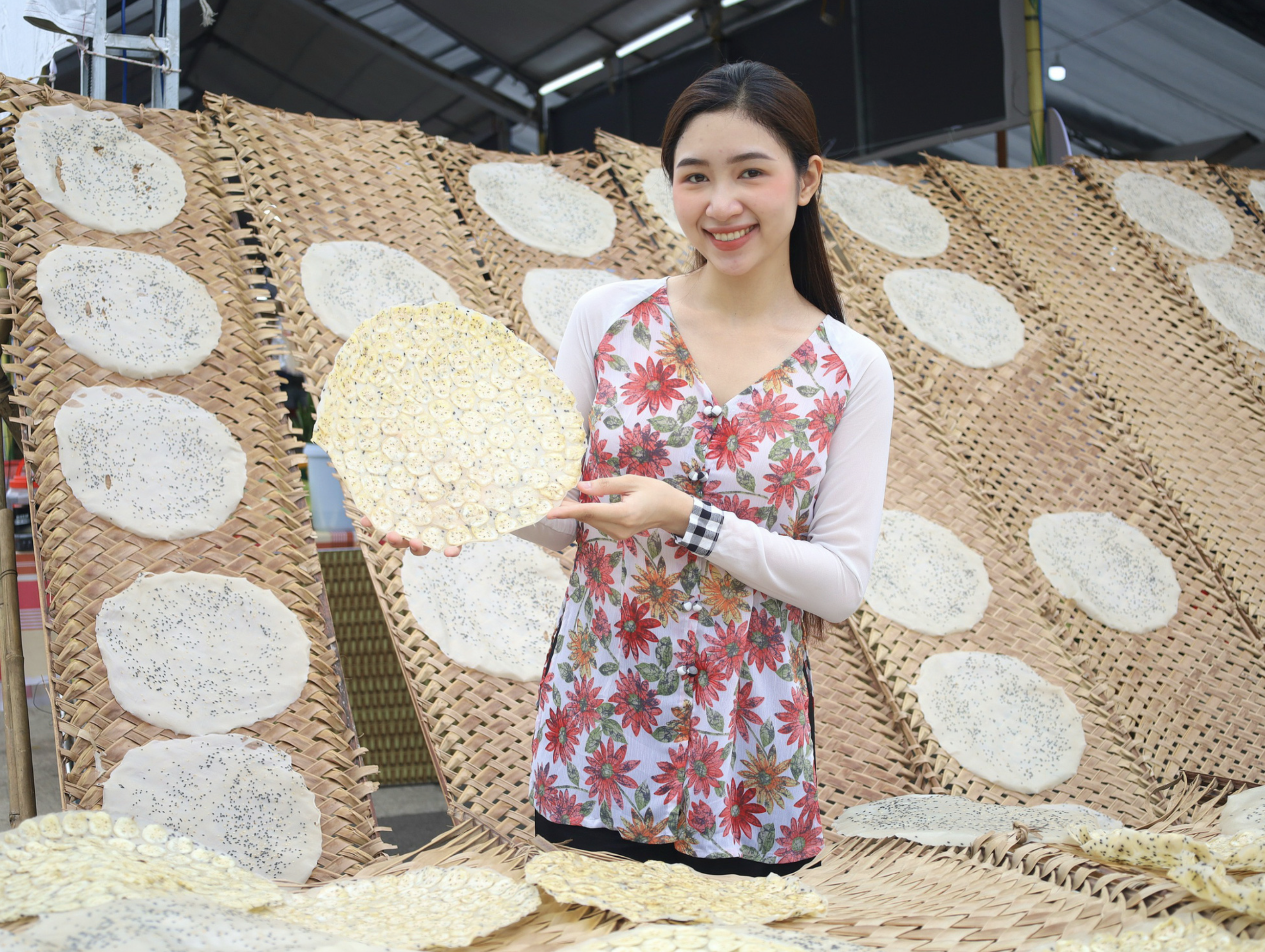 A woman poses for a photo with rice paper at a miniature of the Thuan Hung rice paper craft village at the Southern Folk Cake Festival 2024 launched in Can Tho City on April 17, 2024. Photo: Trung Pham / Tuoi Tre