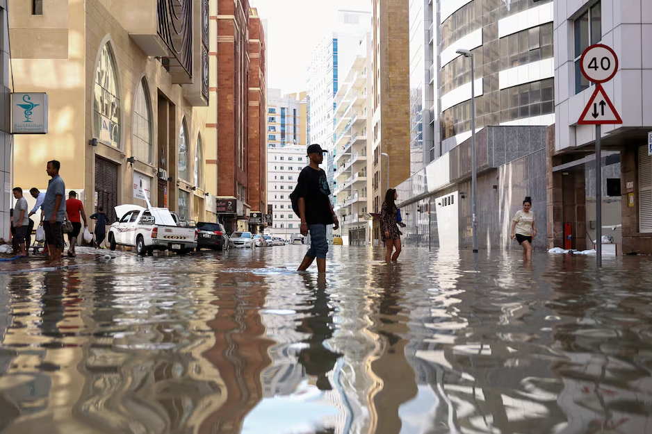People walk through flood water caused by heavy rains, in Dubai, United Arab Emirates, April 17, 2024. Photo: Reuters