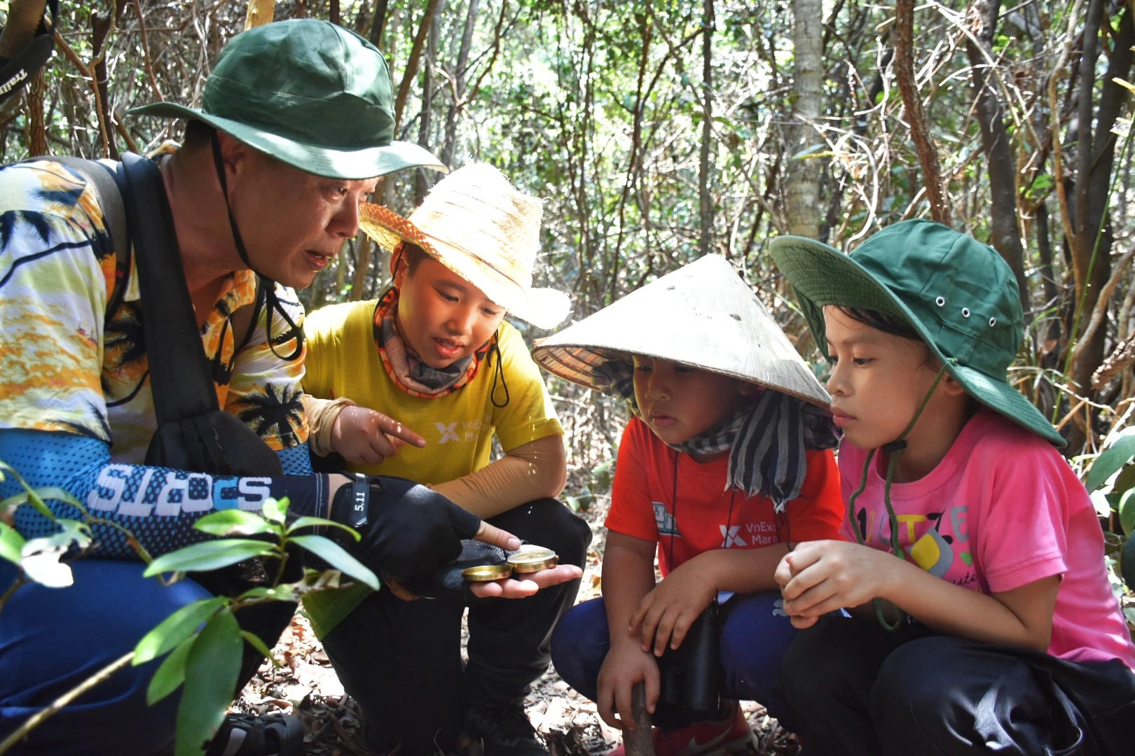 A man instructs the children how to use a compass in the forest. Photo: Tran Hoai