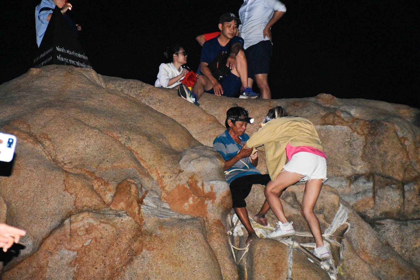 A man helps a tourist to climb up a big rock. Photo: Tran Hoai