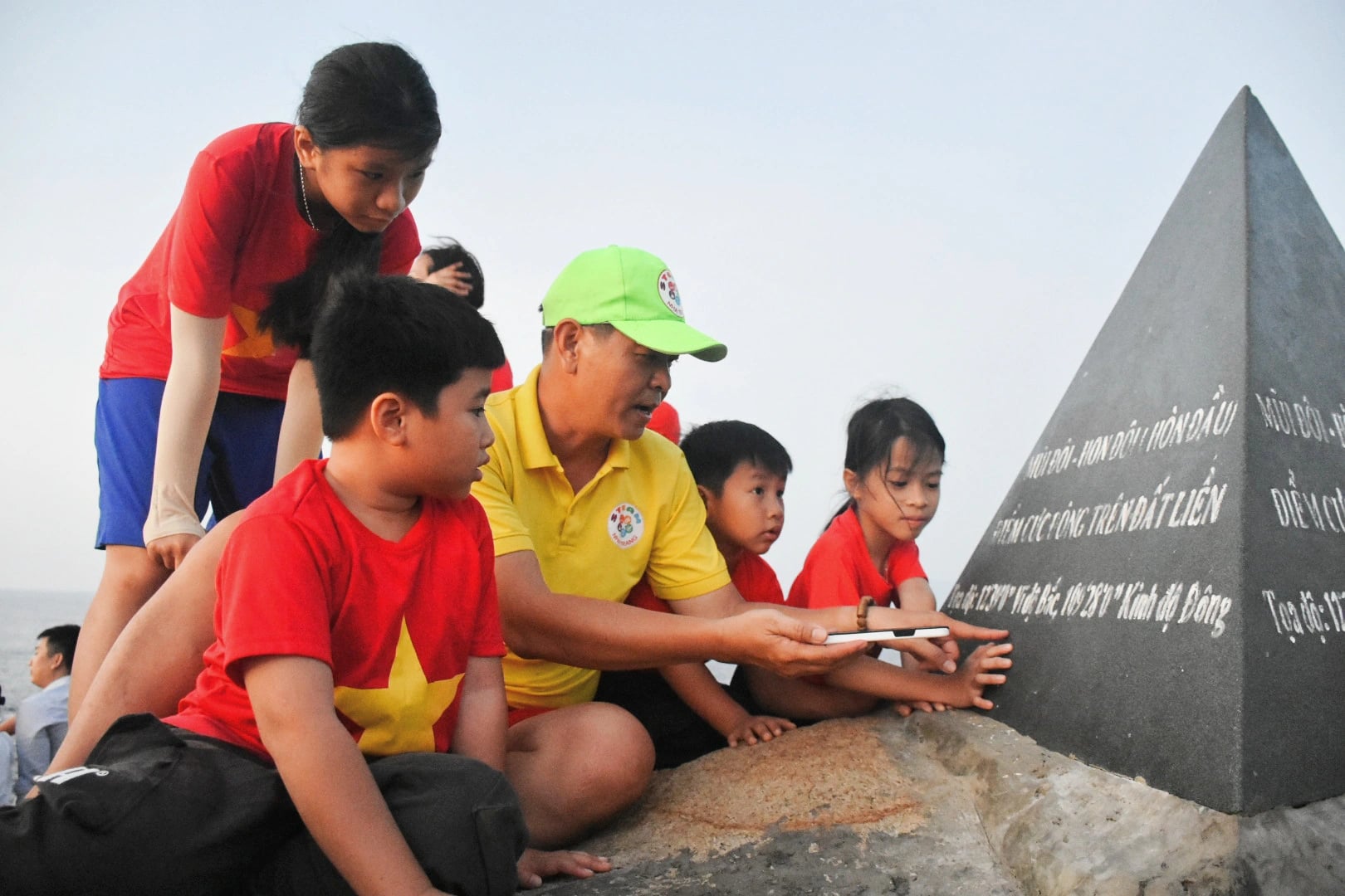 A man instructs the children about the coordinates and information on the landmark at Vietnam mainland's easternmost point. Photo: Tran Hoai