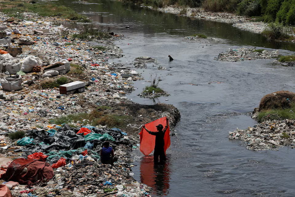 A man washes waste plastic sheets, collected for recycling, in the polluted waters on World Environment Day in Karachi, Pakistan June 5, 2023. Photo: Reuters