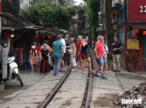 A tour guide introduces the trackside café street in Hanoi to a group of international tourists. Photo: T.T.D. / Tuoi Tre