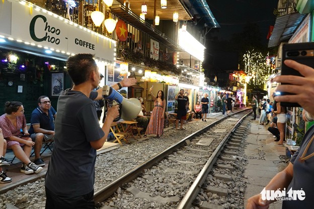 A man holds a hand speaker to inform that a train is approaching. Photo: T.T.D. / Tuoi Tre