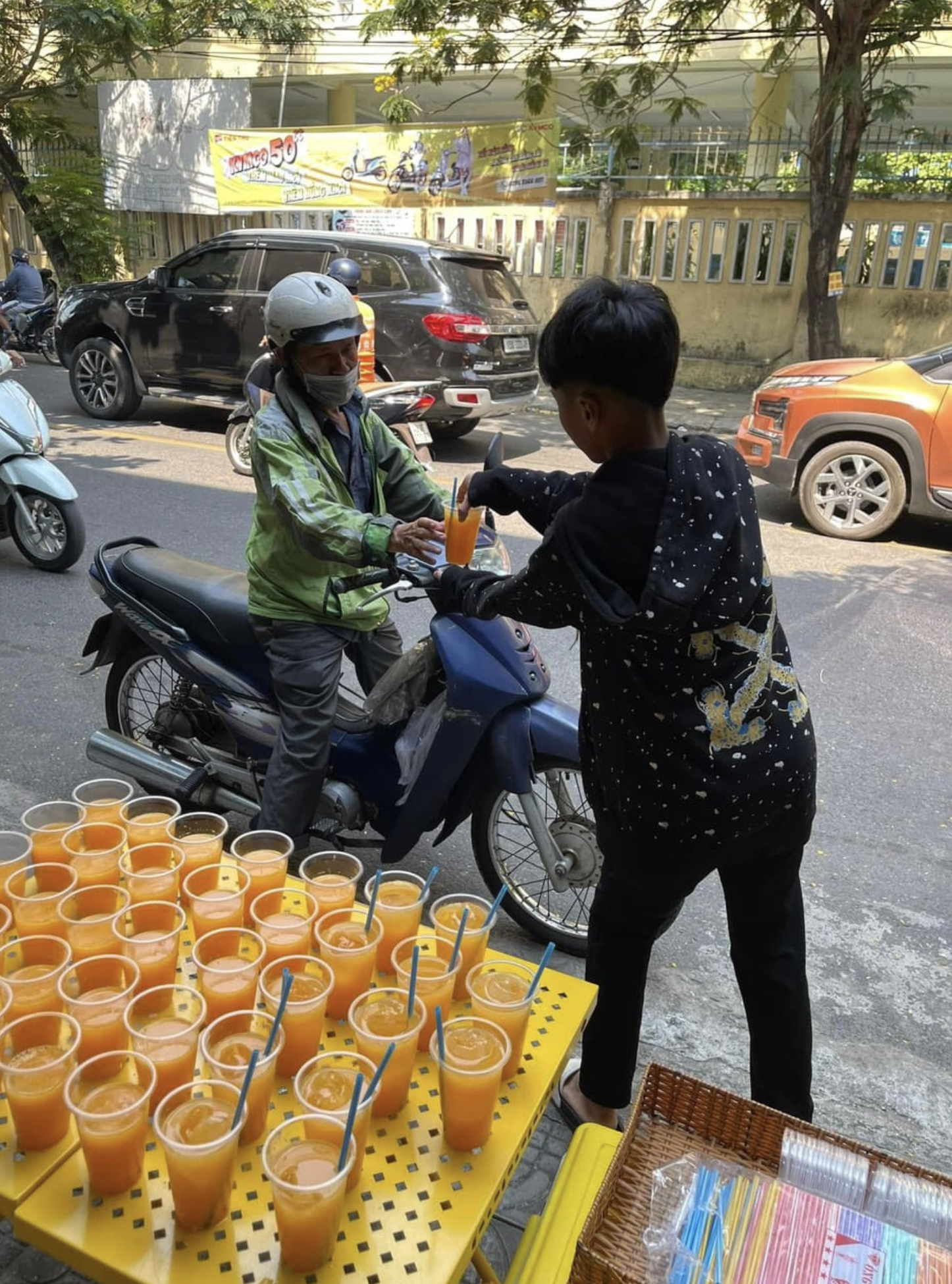 A boy gives a glass of orange juice to a man amid intense heat in Da Nang City