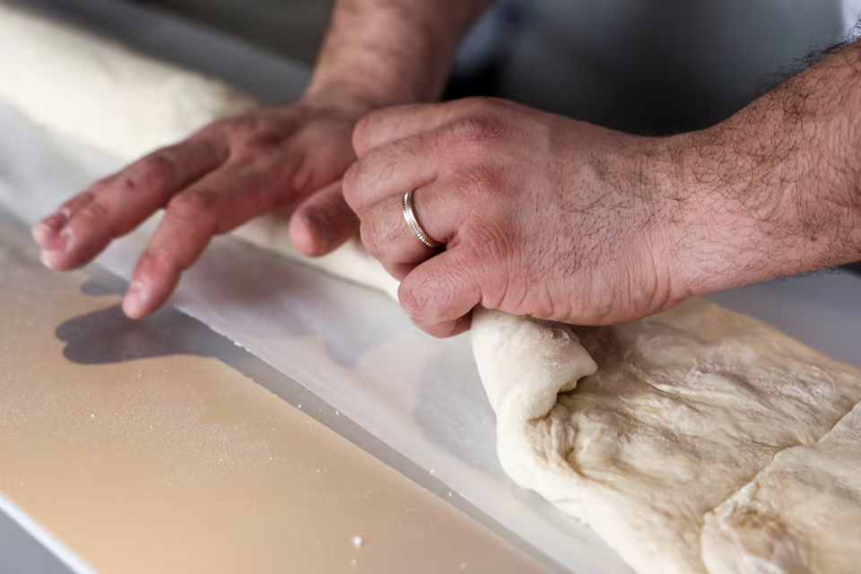 A French baker shapes the baguette as he stands near a large rotating oven in an attempt to beat the world record for the longest baguette during the Suresnes Baguette Show in Suresnes near Paris, France, May 5, 2024. Photo: Reuters