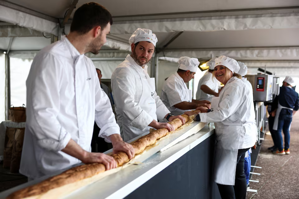 French bakers stand near a large rotating oven in an attempt to beat the world record for the longest baguette during the Suresnes Baguette Show in Suresnes near Paris, France, May 5, 2024. Photo: Reuters