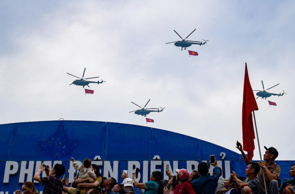 Military helicopters carrying Vietnam’s national flag fly in the sky in Dien Bien Province to mark the 70th anniversary of  the Dien Bien Phu victory on May 7, 2024. Photo: Nam Tran / Tuoi Tre