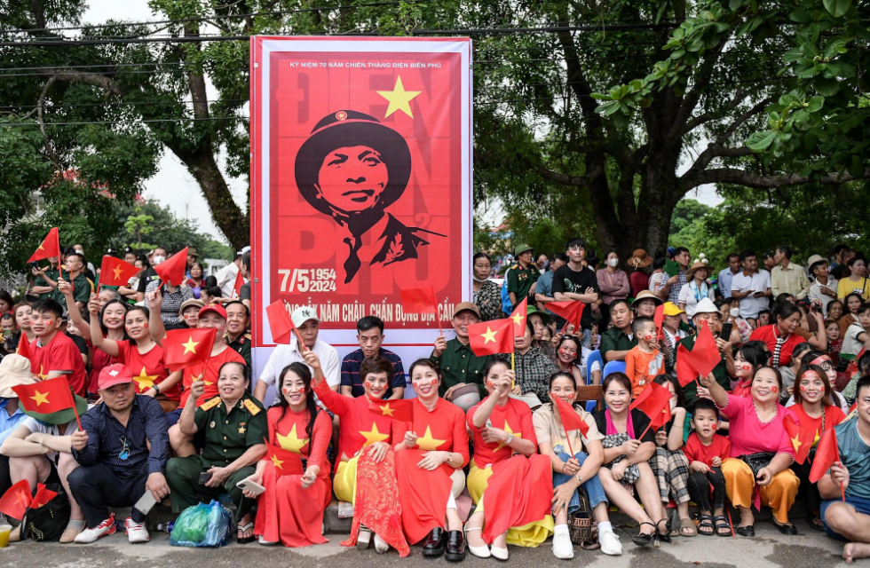 Locals and tourists holding and waving Vietnam’s national flag wait for a military parade on a local street in Dien Bien Province to celebrate the 70th anniversary of the Dien Bien Phu victory. Photo: Nam Tran / Tuoi Tre