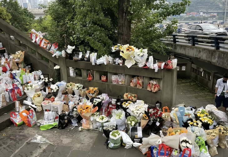 This screenshot shows bouquets of flowers placed by Chinese people on the bridge where Fat Cat committed suicide to express their condolences to the death of the young man.