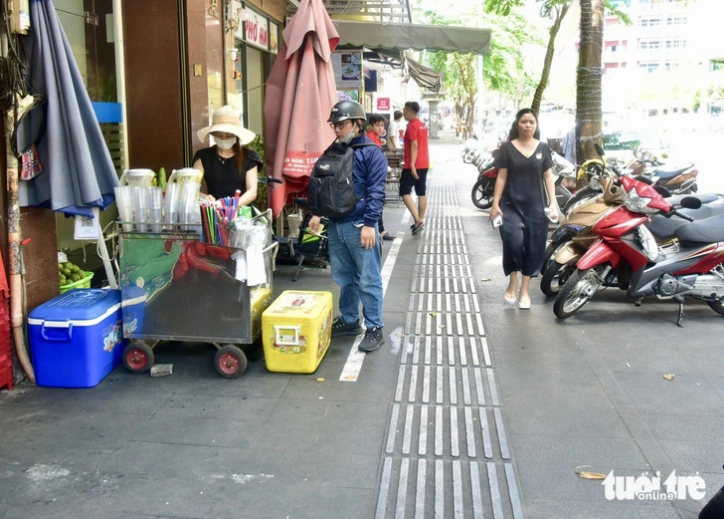 Le Thi Khuyen (L), a drink vendor on Hai Trieu Street in District 1, Ho Chi Minh City, says she plans to register the use of part of the sidewalk on the street. Photo: T.T.D. / Tuoi Tre