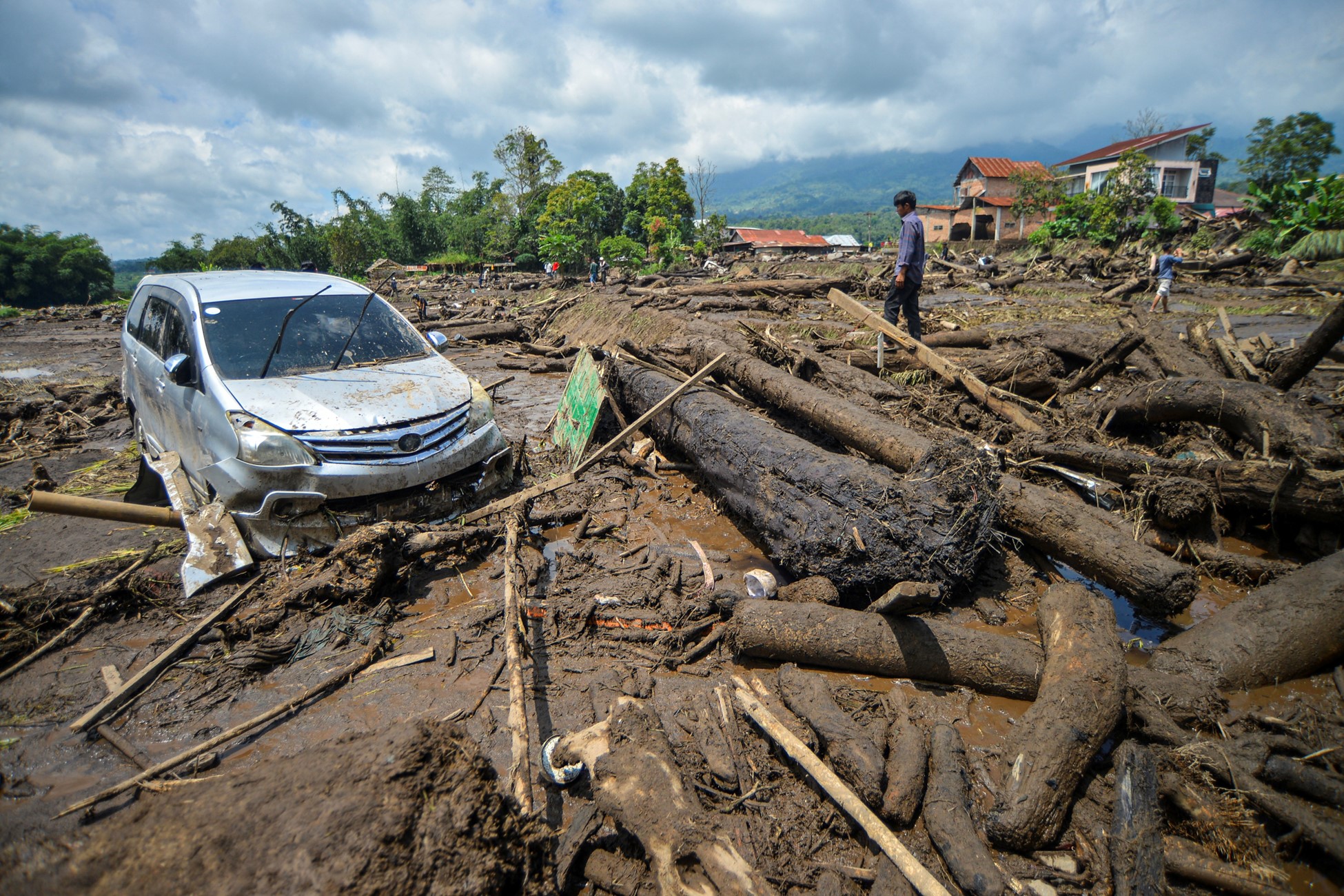 A man stands near a damaged car in an area area affected by heavy rain brought flash floods and landslides in Agam, West Sumatra province, Indonesia, May 12, 2024.