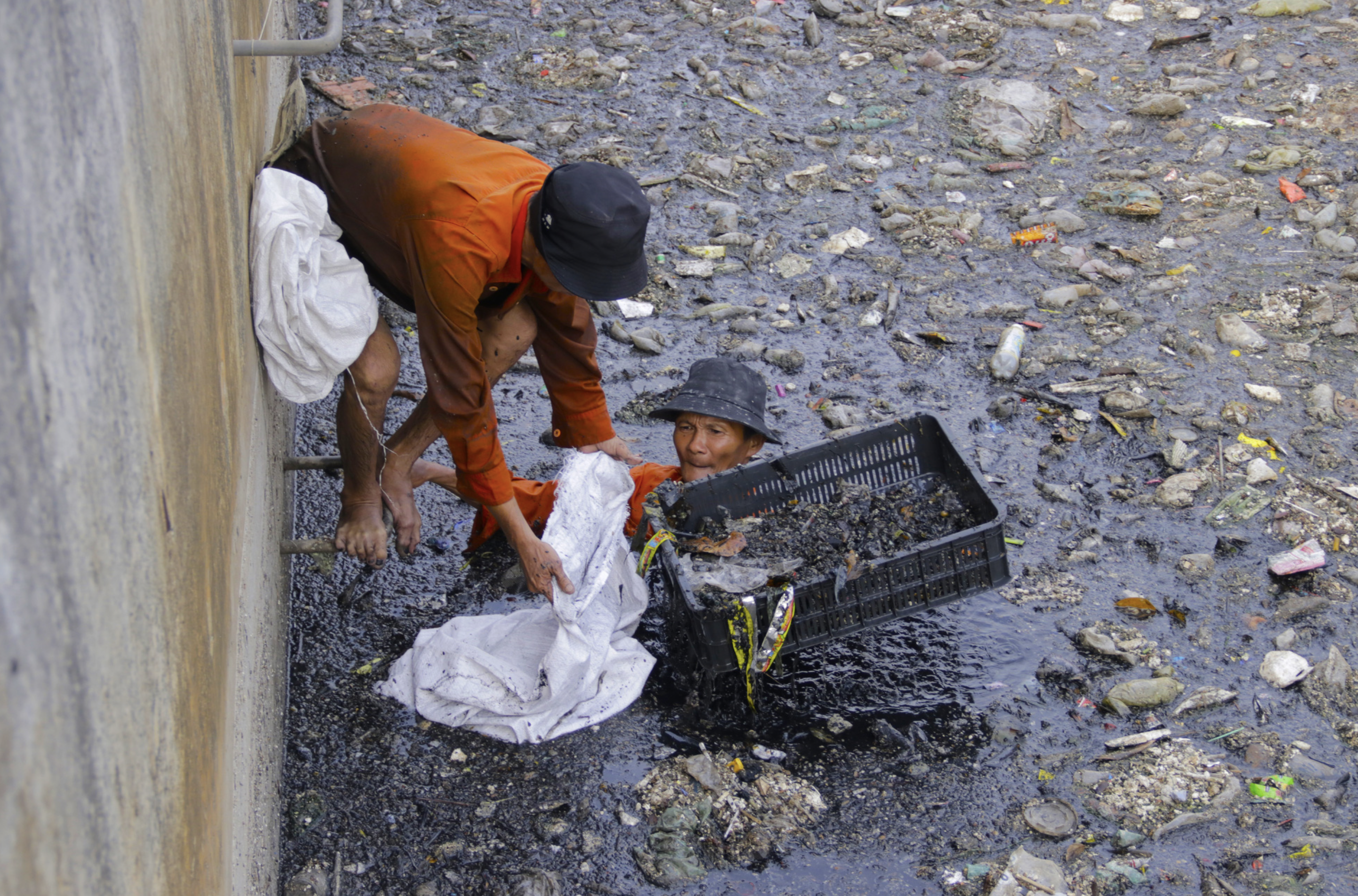Sanitation workers wade in the water to remove trash from the polluted canal in Binh Hung Hoa Ward in Binh Tan District, Ho Chi Minh City on May 13, 2024. Photo: Tien Quoc / Tuoi Tre