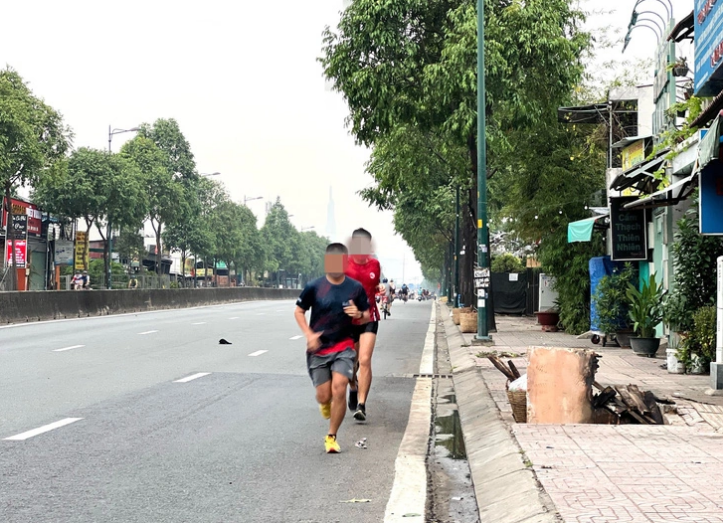 Two people run in the opposite direction on Pham Van Dong Street in Ho Chi Minh City. Photo: Xuan Doan / Tuoi Tre