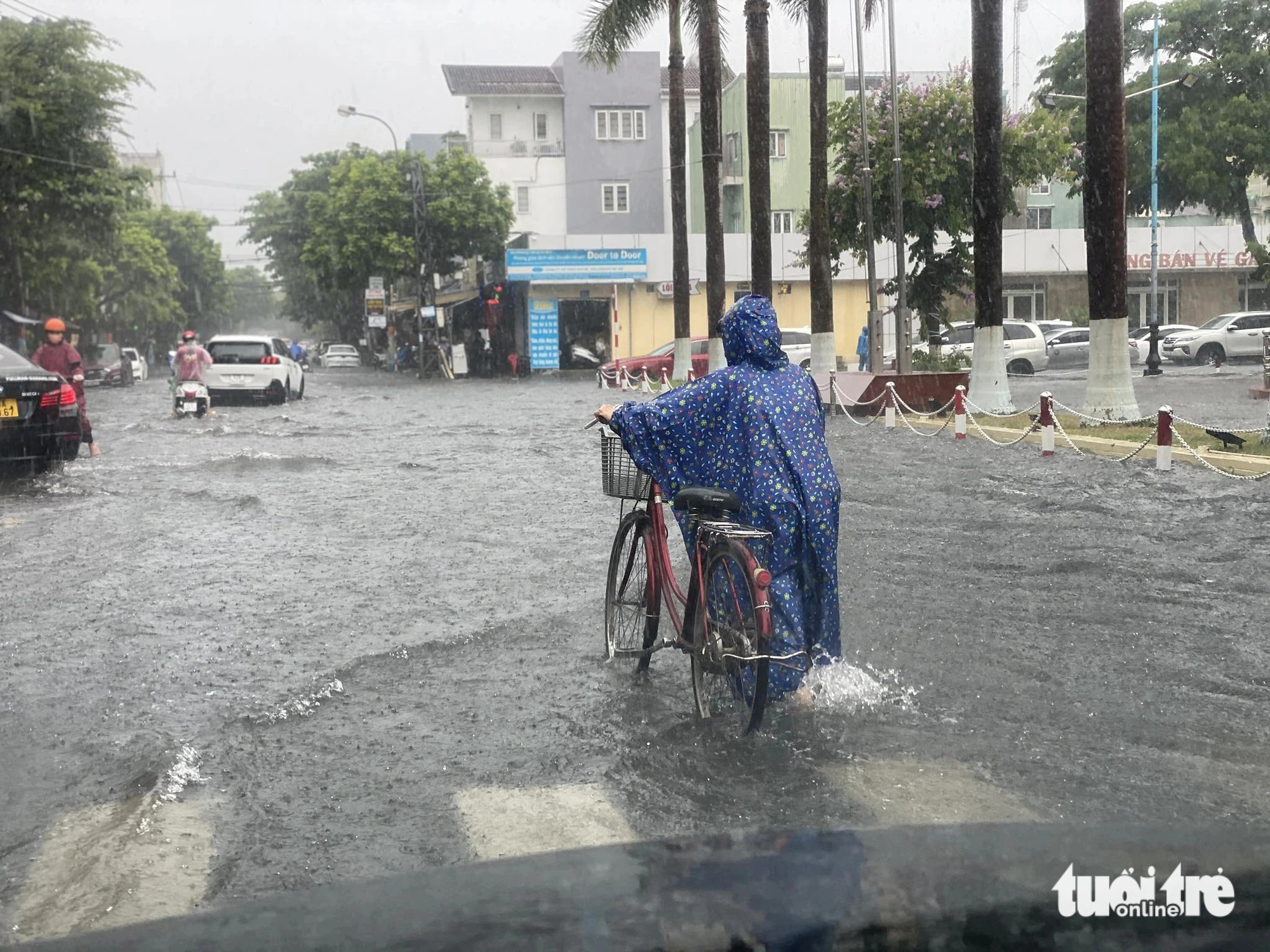 A cyclist wades through a flooded street in front of a train station in Da Nang City, central Vietnam. Photo: Ba Dung / Tuoi Tre