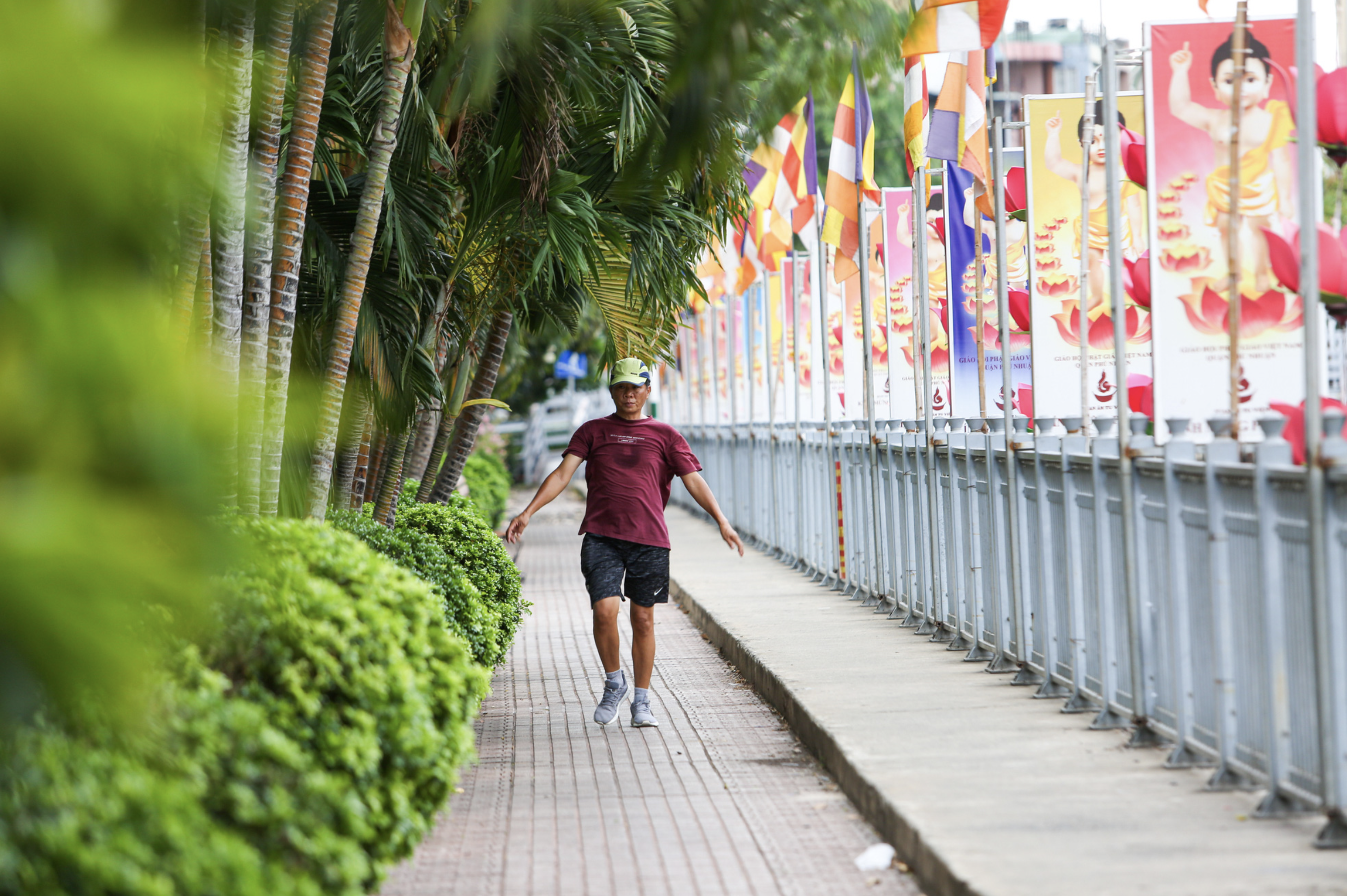A man does exercise along Nhieu Loc - Thi Nghe Canal strung with colorful Buddhist flags. Photo: Phuong Quyen / Tuoi Tre