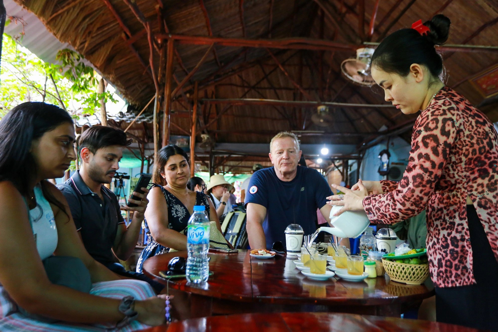 Foreign travelers are seen waiting to enjoy tea with honey offered by a woman at a beekeeping farm on Thoi Son Isle, located on the Tien River in Tien Giang Province, southern Vietnam. Photo: Phuong Quyen / Tuoi Tre