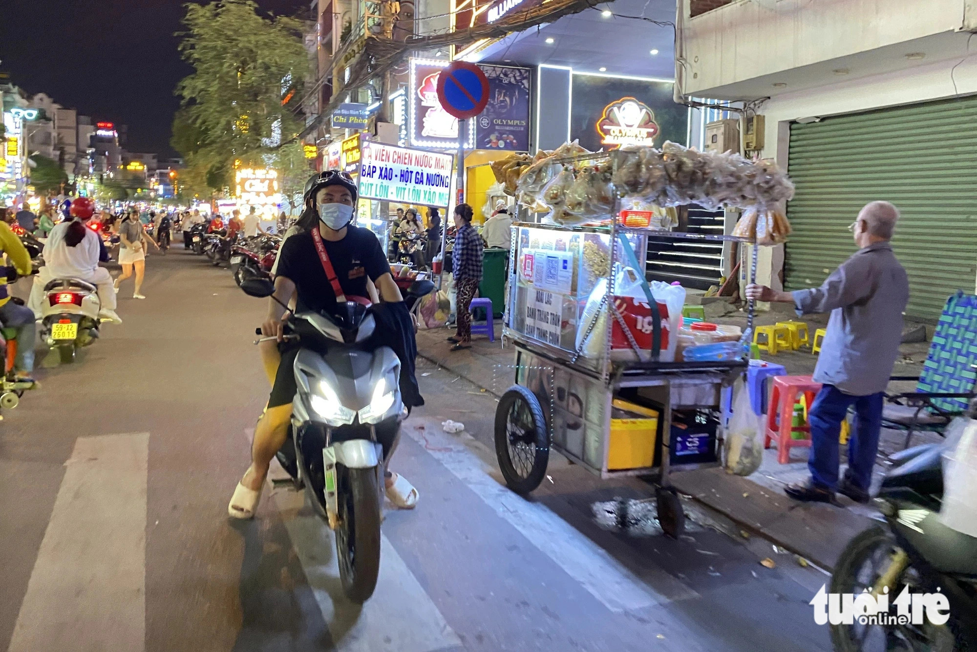 A motorcyclist is seen riding in the wrong direction to buy items from food cart operators that encroach on Nguyen Gia Tri Street, located in Ward 25, Binh Thanh District, Ho Chi Minh City. Photo: Tien Quoc / Tuoi Tre