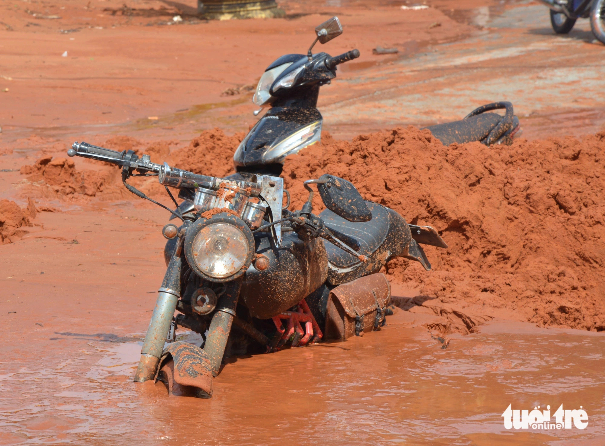 Many commuters quickly escaped a flood of red sand and mud, leaving behind their vehicles which were stuck in the mud. Photo: Duc Trong / Tuoi Tre
