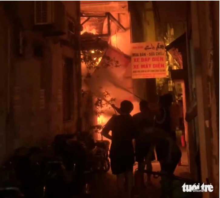 Local residents use fire extinguishers to put out the blaze. Photo: Hoai An / Tuoi Tre
