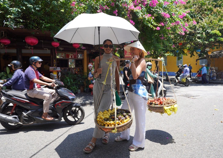 One of the 28 Miss Universe Australia 2024 finalists poses for a photo with a street vendor in Ancient Hoi An Town, Quang Nam Province, central Vietnam, May 25, 2024. Photo: Bao Chau / Tuoi Tre