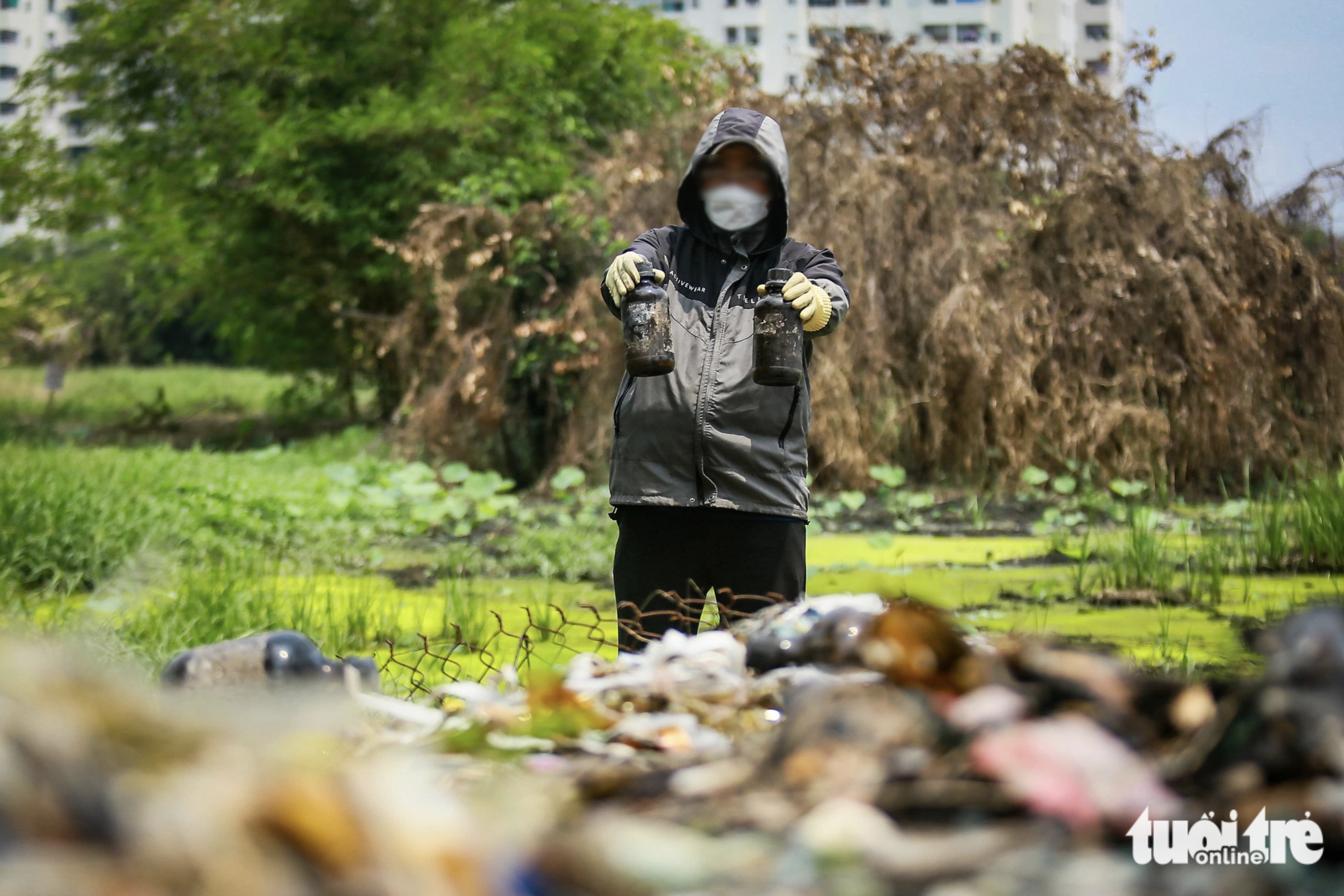 Glass bottles and medical waste litter an area along a swamp in Binh Tan District, Ho Chi Minh City. Photo: Chau Tuan / Tuoi Tre