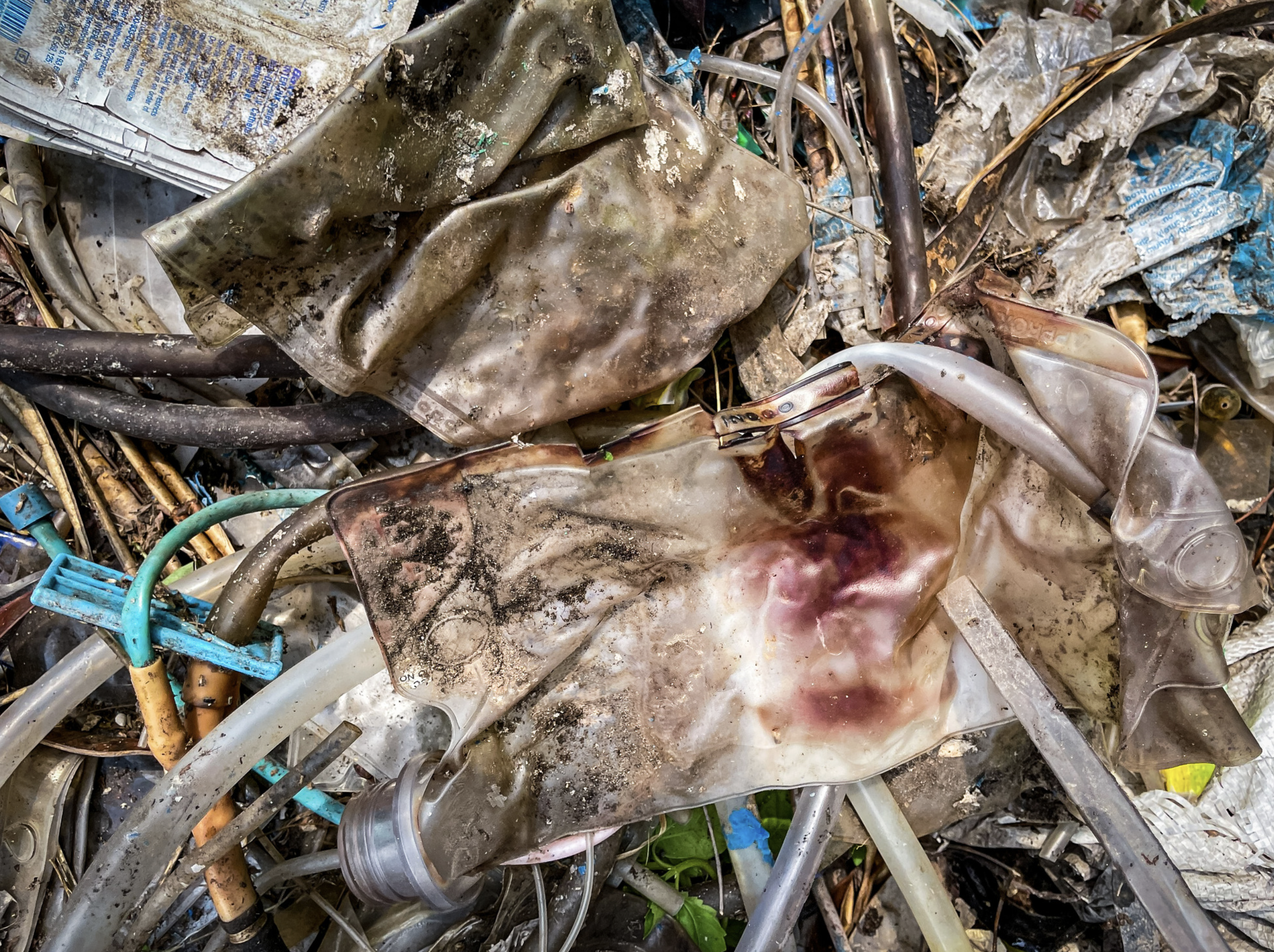 Plastic bags and vials litter an area of land near a swamp in Binh Tan District. Photo: Ngoc Khai / Tuoi Tre