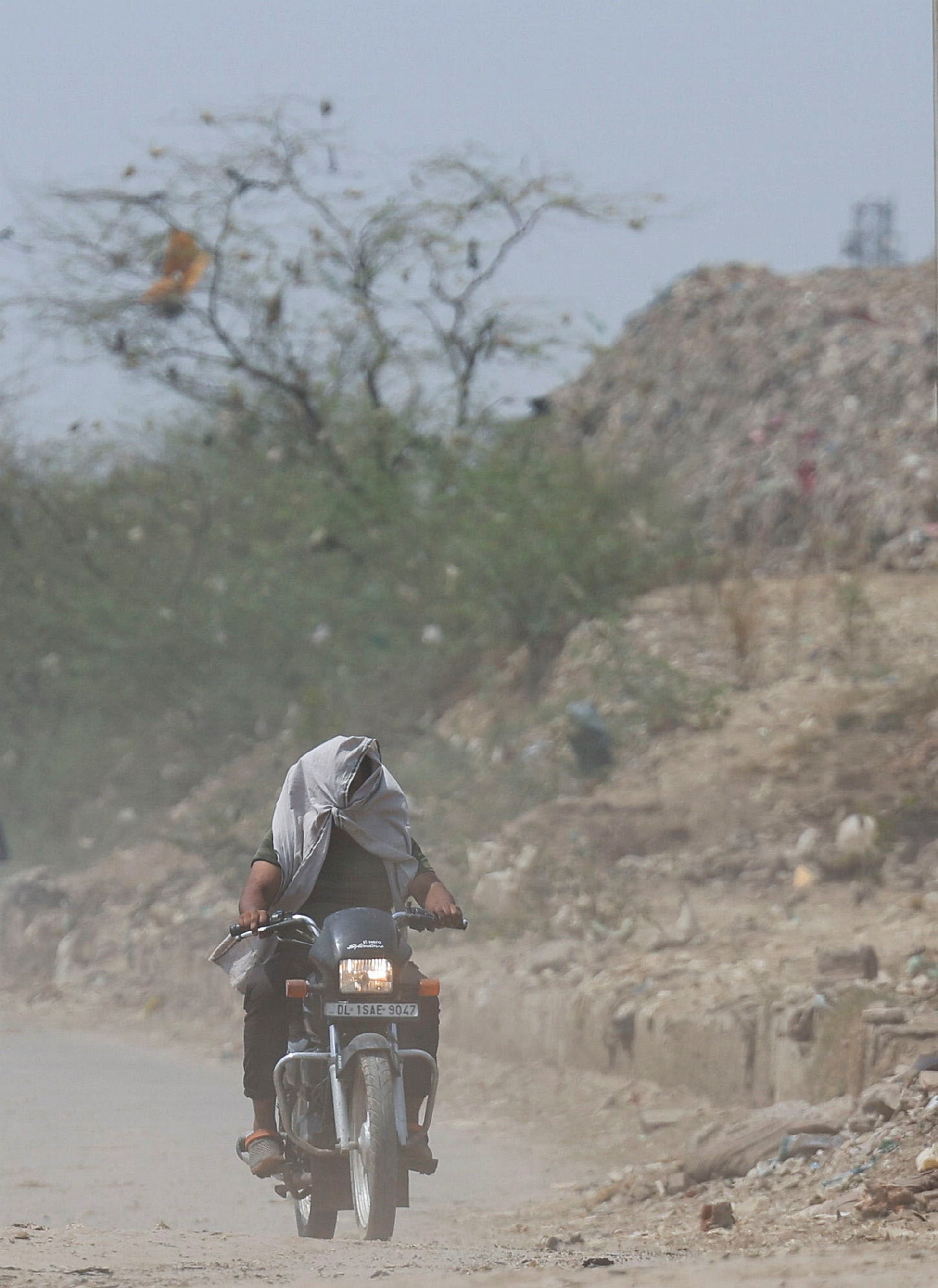 A man rides his bike near a landfill site on a hot summer day during a heatwave in New Delhi, India, May 27, 2024. Photo: Reuters