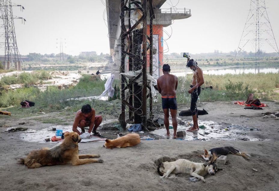 People bath from a broken water pipeline on the Yamuna river bed under a bridge on a hot summer day in New Delhi, India, May 22, 2024. Photo: Reuters