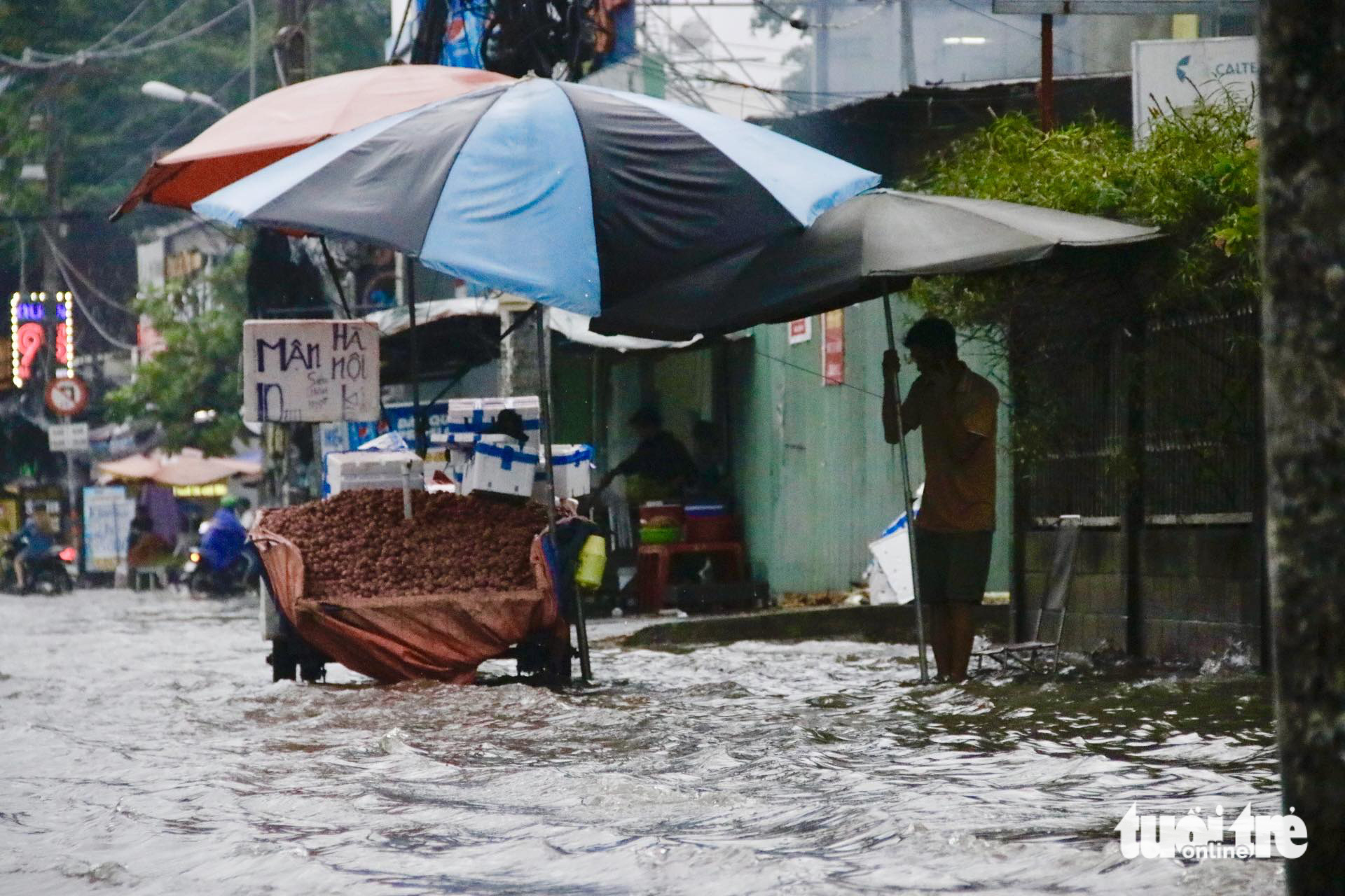 A street vendor is seen handling his stall on the heavily-flooded Ung Van Khiem Street in Binh Thanh District, Ho Chi Minh City on May 31, 2024. Photo: Tien Quoc / Tuoi Tre