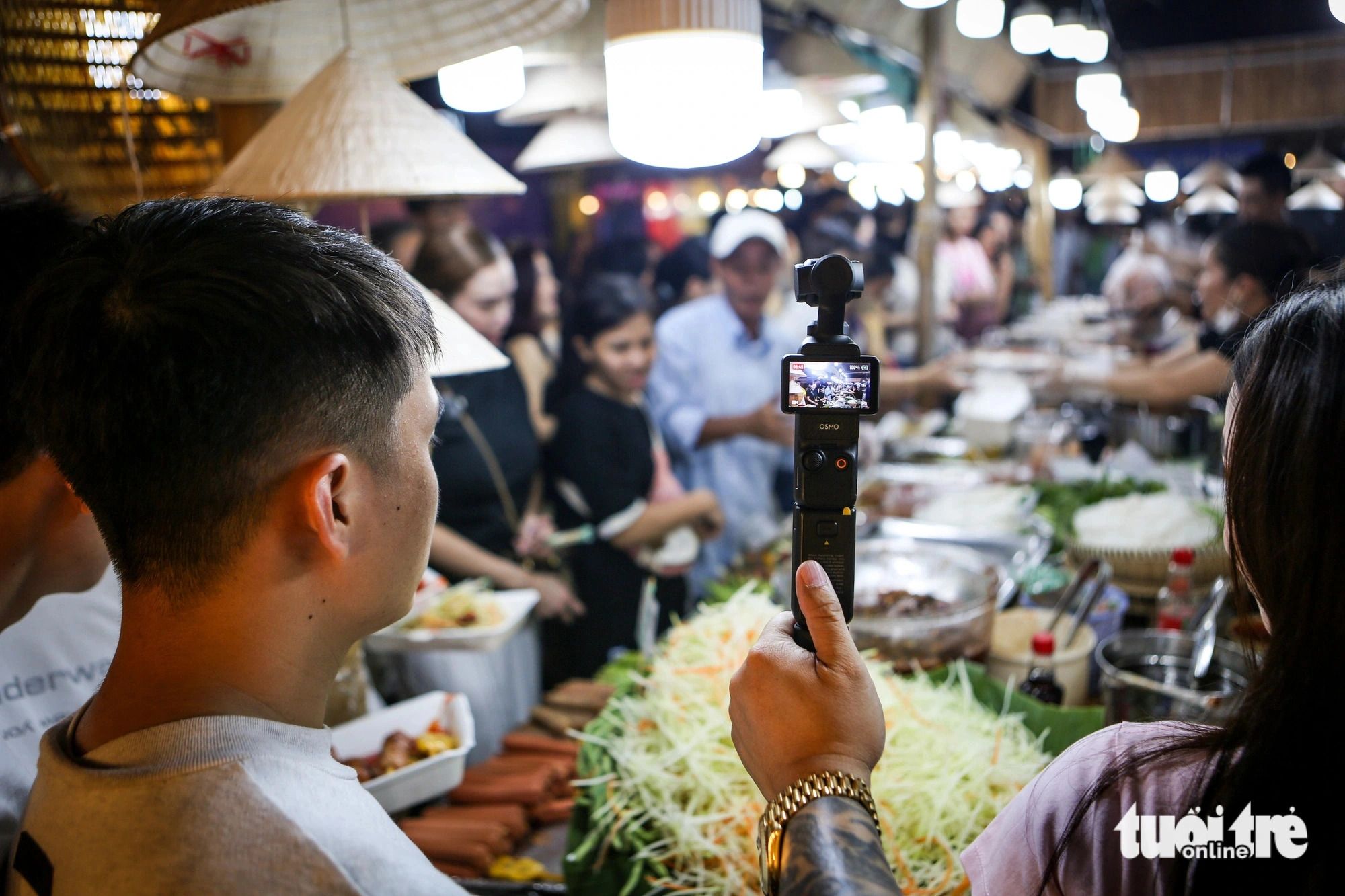 A Youtuber is seen filming a scene of the cuisine event held along Le Loi Boulevard in District 1, Ho Chi Minh City. Photo: Phuong Quyen / Tuoi Tre