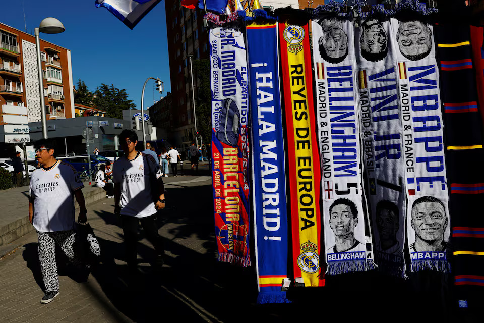 Real Madrid fans walk past a stand selling football scarves of Jude Bellingham, Vinicius Junior and Kylian Mbappe, outside Real Madrid’s Santiago Bernabeu stadium in Madrid, Spain, April 21, 2024. Photo: Reuters