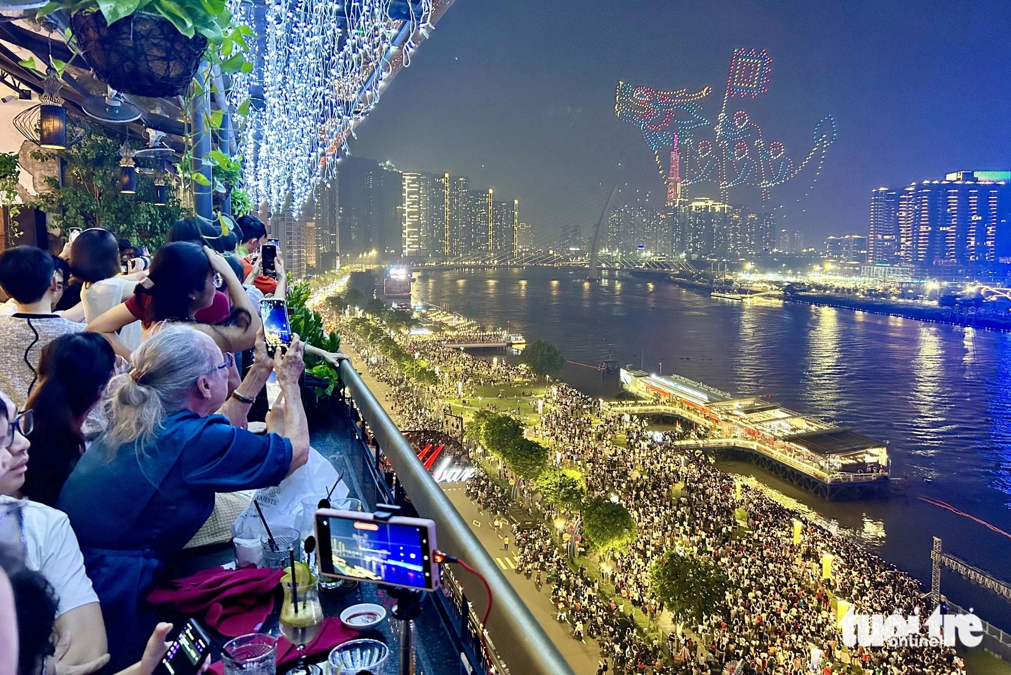 Local residents and visitors capture their favorite moments of a drone light show over the Saigon River in Ho Chi Minh City, June 9, 2024. Photo: T.T.D / Tuoi Tre