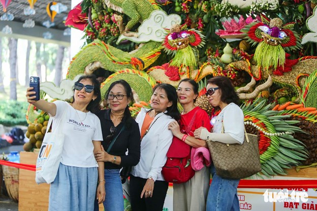 Visitors pose for a photo with a fruit sculpture.