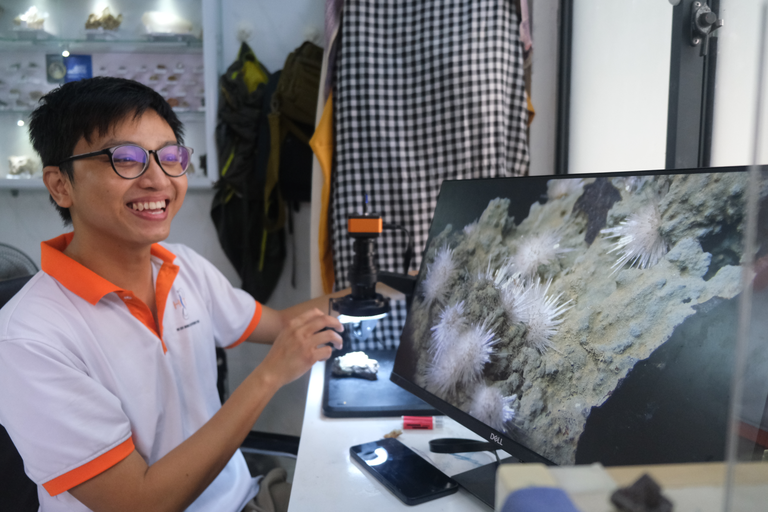 Tuyen examines a mineral sample under a microscope. Photo: Ngoc Phuong / Tuoi Tre News